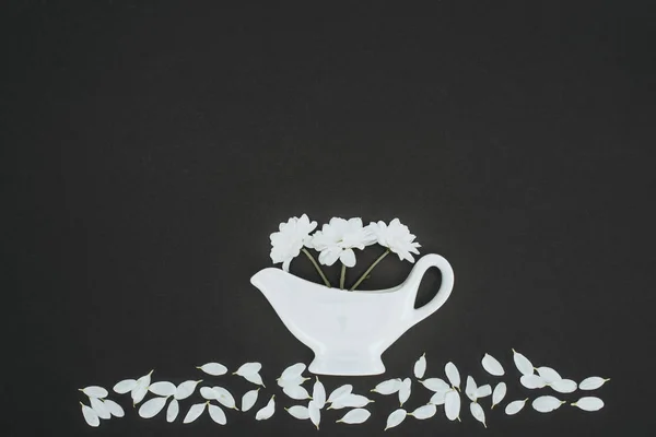 Vue de dessus de théière blanche avec des fleurs de marguerite sur fond noir — Photo de stock