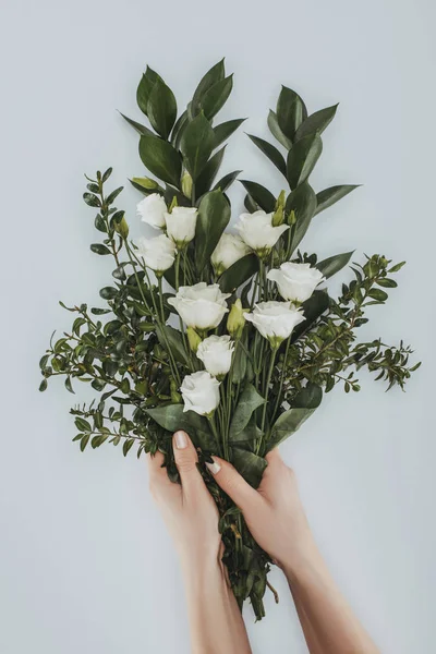 Cropped image of female hands holding bouquet with eustoma flowers isolated on grey — Stock Photo