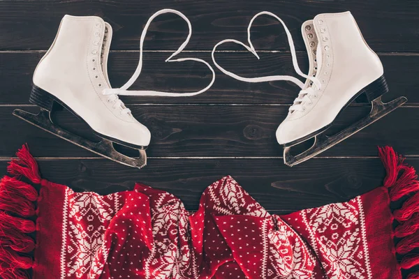 Vue du dessus des patins blancs avec des lacets en forme de coeur et une écharpe sur le dessus de la table — Photo de stock