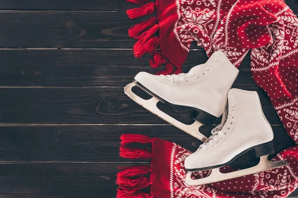 Vue de dessus de paire de patins blancs et foulard rouge sur table en bois — Photo de stock