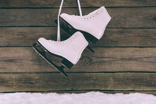 Par de patines blancos colgando en la pared de madera con cordones de zapatos - foto de stock