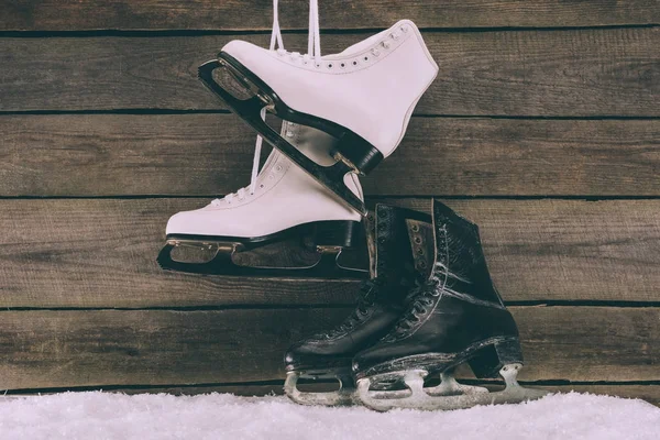 Paar weiße und schwarze Schlittschuhe in der Nähe der Holzwand — Stockfoto