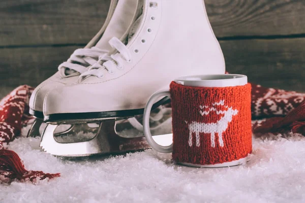 Par de patins brancos com copo com ornamento de malha e cachecol — Fotografia de Stock