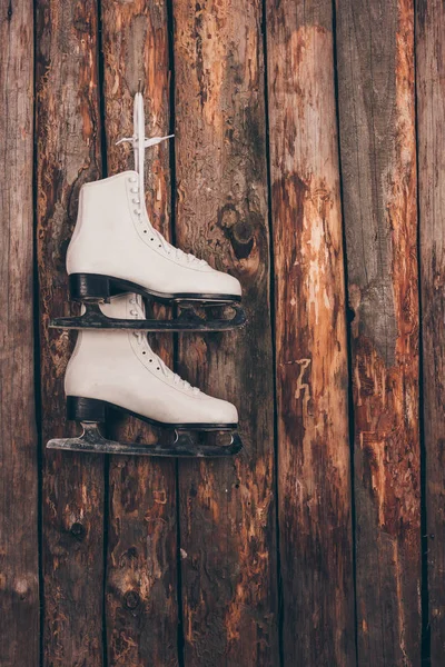 Pair of white skates hanging on wooden shabby wall — Stock Photo