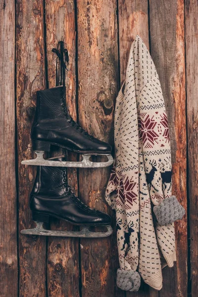 Warm sweater and pair of black skates hanging on wooden wall — Stock Photo