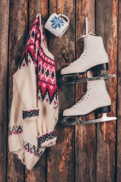 Sweater with cup and pair of skates hanging on shabby wall — Stock Photo