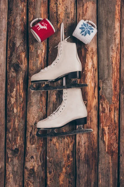 Deux tasses et une paire de patins blancs suspendus au mur en bois — Photo de stock