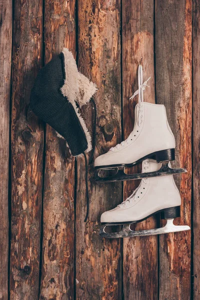 Hat with ear flaps and pair of skates hanging on wooden wall — Stock Photo