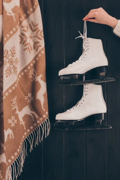 Imagen recortada de mujer sosteniendo par de patines blancos con cordones de zapatos - foto de stock