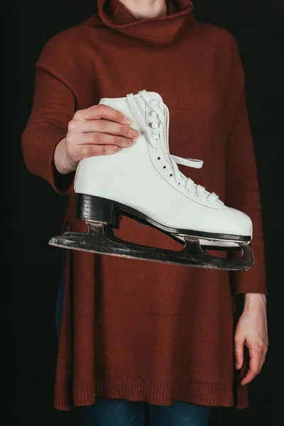 Imagen recortada de la mujer en la celebración de par de patines blancos aislados en negro - foto de stock