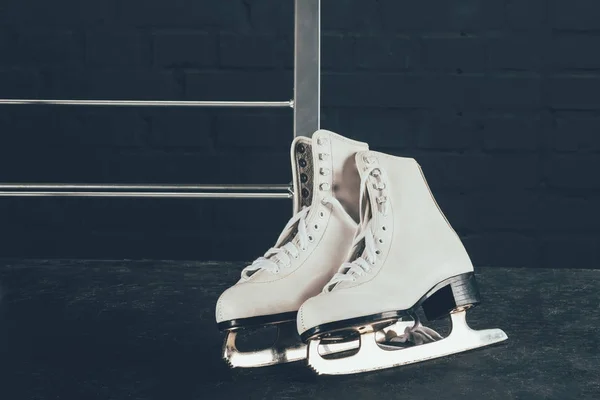 Pair of white figure skates on gray floor — Stock Photo