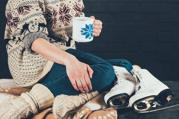 Cropped image of woman sitting on blanket and holding cup of tea — Stock Photo