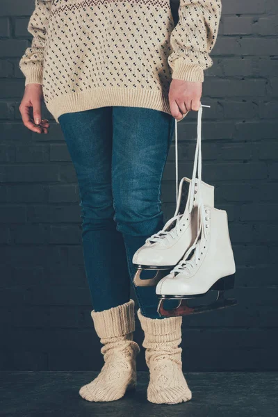 Cropped image of woman standing and holding skates with shoelaces — Stock Photo