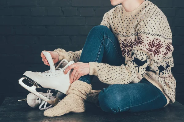 Cropped image of woman sitting on gray floor and wearing white skates — Stock Photo