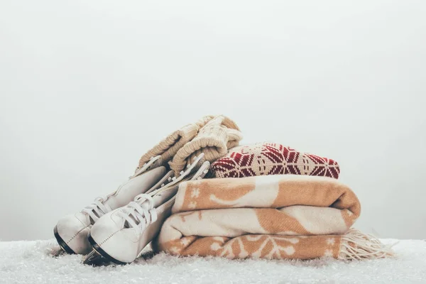 Білі ковзани зі стопкою ковдри та светру на снігу — стокове фото