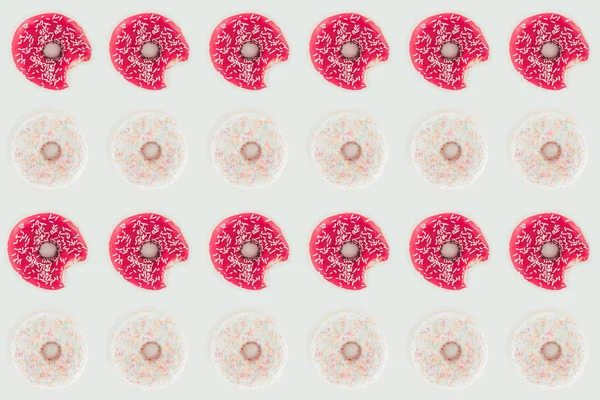 Vista superior del patrón sin costuras de filas de rosadas y blancas sabrosas rosquillas aisladas en blanco - foto de stock