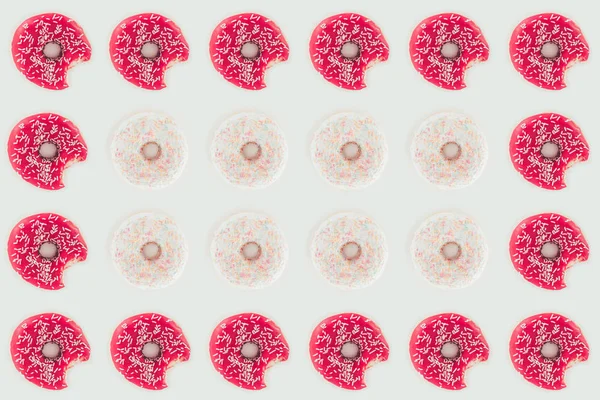 Вид сверху на бесшовный рисунок укушенных розовых и белых пончиков, изолированных на белом — стоковое фото