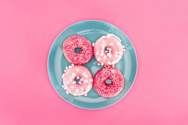 Vista superior de rosquillas vidriadas en placa aislada en rosa - foto de stock