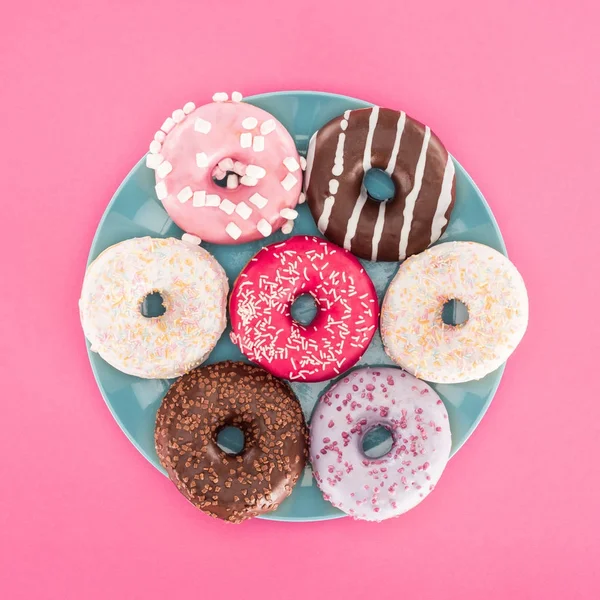 Top view of various glazed doughnuts on plate isolated on pink — Stock Photo