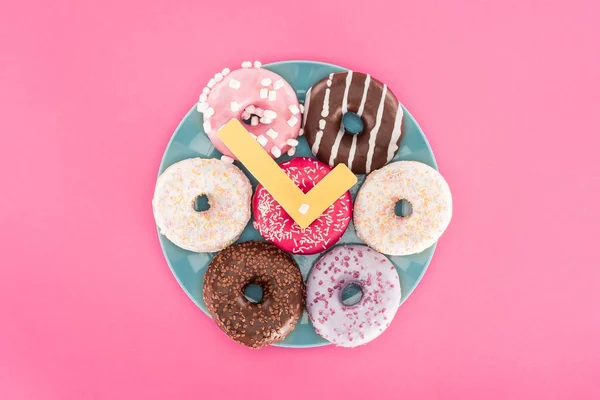 Top view of clock made of doughnuts on plate isolated on pink — Stock Photo