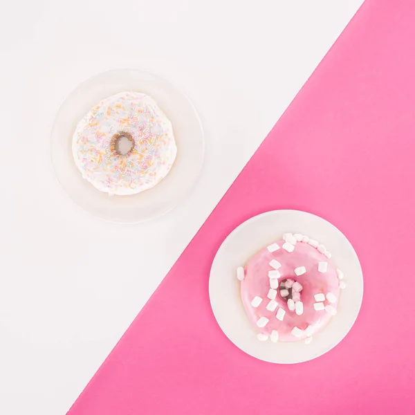 Draufsicht auf verschiedene glasierte Donuts auf überzogener weißer und rosa Oberfläche — Stockfoto
