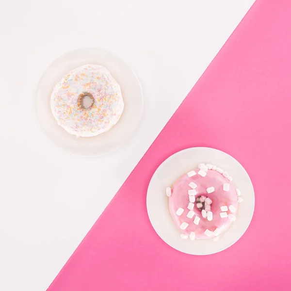 Top view of various glazed doughnuts on plated on white and pink surface — Stock Photo