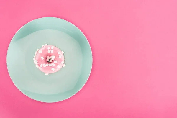 Вид сверху на глазированный пончик с зефиром на тарелке, изолированной на розовом — стоковое фото