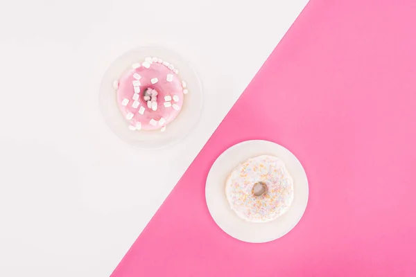 Vista superior de vários donuts envidraçados em banhado na superfície branca e rosa — Fotografia de Stock