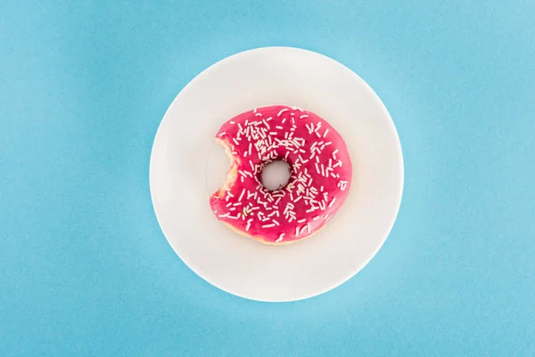 Вид сверху на укушенные розовые глазурованные пончики на тарелке — стоковое фото