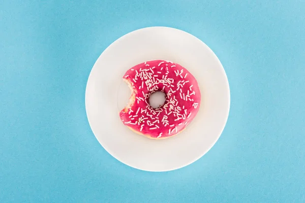 Vue du dessus du beignet glacé rose mordu sur plaque — Photo de stock