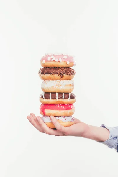 Cropped shot of woman holding stack of tasty doughnuts isolated on white — Stock Photo