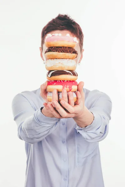 Woman holding stack of doughnuts in front of face isolated on white — Stock Photo