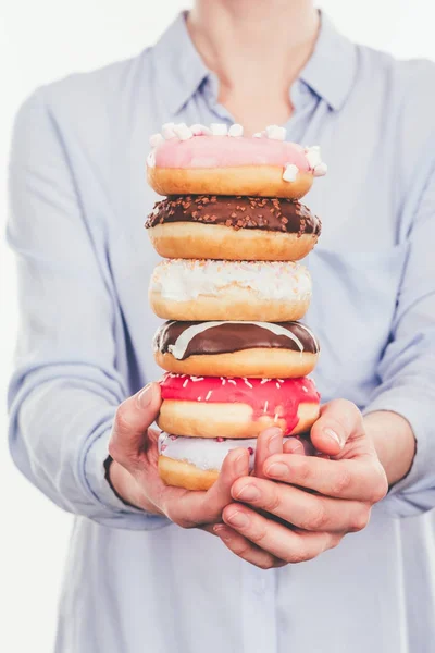 Colpo ritagliato di donna che tiene pila di ciambelle isolate su bianco — Foto stock