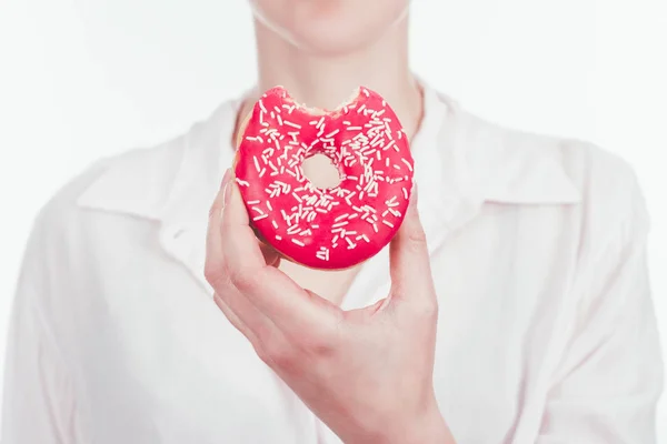 Обрізаний знімок жінки, що тримає кусаний глазурований пончик — стокове фото