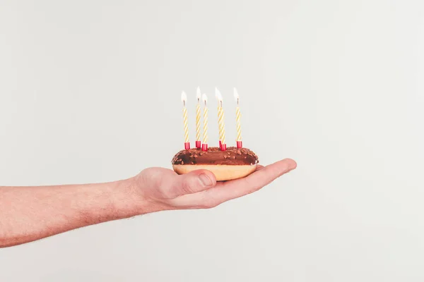 Tiro recortado de mujer sosteniendo donut con vela de cumpleaños - foto de stock