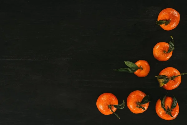 Top view of ripe tangerines on black wooden surface — Stock Photo