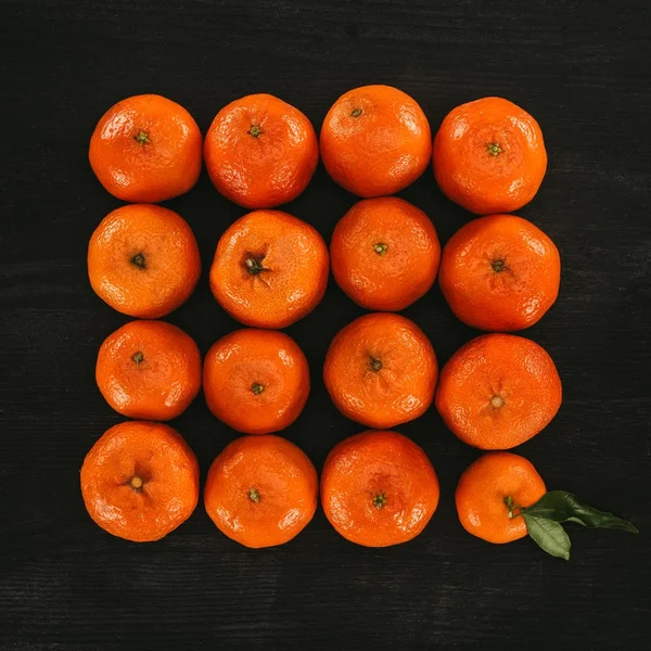 Vista superior de tangerinas dispostas em quadrado na superfície de madeira preta — Fotografia de Stock