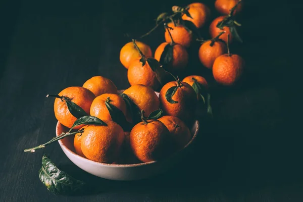 Vista de perto de tangerinas em tigela em mesa de madeira escura — Fotografia de Stock