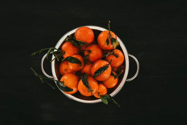 Top view of pile of mandarins in saucepan on black wooden surface — Stock Photo