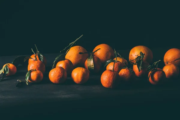 Vista de cerca de mandarinas maduras con hojas en la mesa de madera - foto de stock
