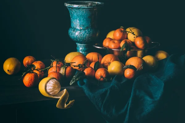 Vista de perto de arranjo de limões frescos e tangerinas em coador na mesa com toalha de mesa escura — Fotografia de Stock