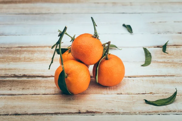 Nahaufnahme von reifen Mandarinen mit Blättern auf hölzerner Tischplatte — Stockfoto