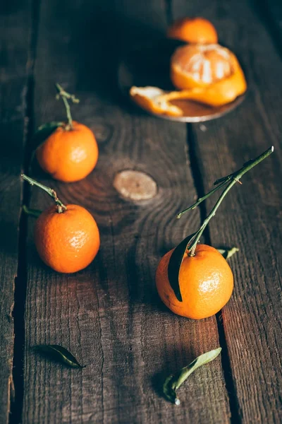 Nahaufnahme von reifen Mandarinen mit Blättern auf hölzerner Tischplatte — Stockfoto