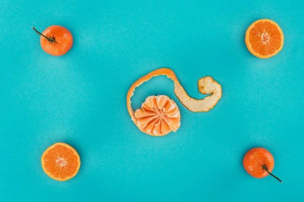 Tendido plano con mandarinas maduras y piezas anaranjadas aisladas en azul - foto de stock