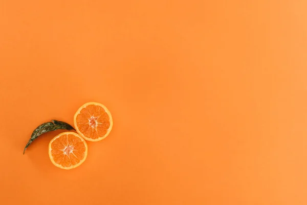 Vue de dessus des morceaux d'orange et de feuille isolés sur l'orange — Photo de stock