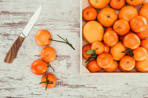 Deitado plano com tangerinas na caixa e faca na mesa de madeira gasto — Fotografia de Stock