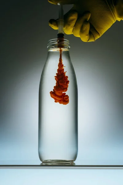 Cropped view of person pouring blood from syringe into bottle with water — Stock Photo