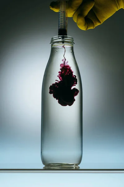 Cropped view of person pouring purple paint into bottle with water — Stock Photo