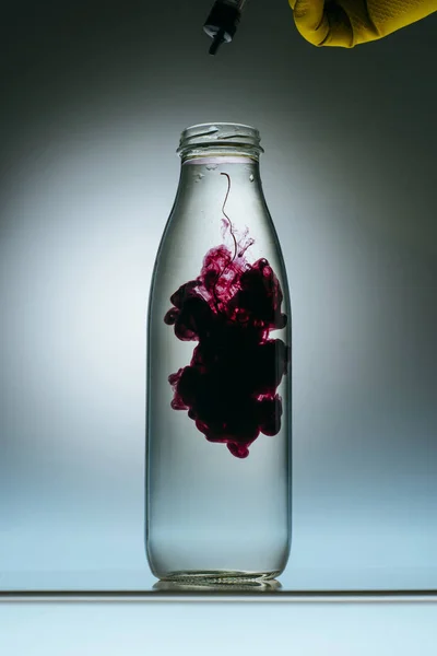 Cropped view of person pouring purple paint into bottle with water — Stock Photo