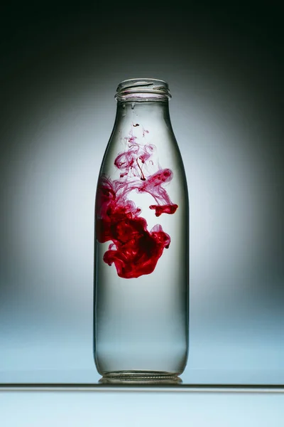 Vista de perto do respingo de tinta vermelha em garrafa de água — Fotografia de Stock